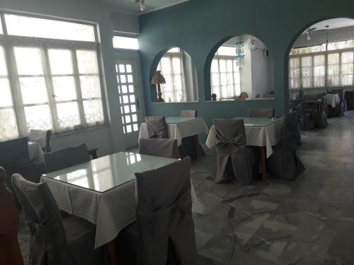 un comedor con mesas, sillas y ventanas en Enalion Beach Hotel, en Paralio Astros