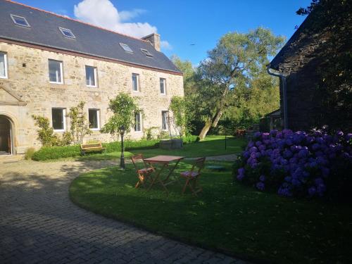 a garden with a table and purple flowers in front of a building at LE DOMAINE DE COAT ROGAN, La chambre du Jaudy in Pommerit-Jaudy