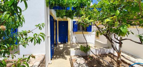 a blue door in a white building with a tree at Stella's Houses in Agia Pelagia Kythira