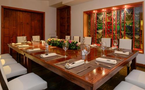 a long wooden table with white chairs and a large table with wine glasses at Hotel Los Juaninos in Morelia