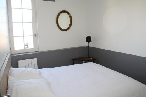 1 dormitorio con cama blanca y espejo en Perhistorique, en Périgueux
