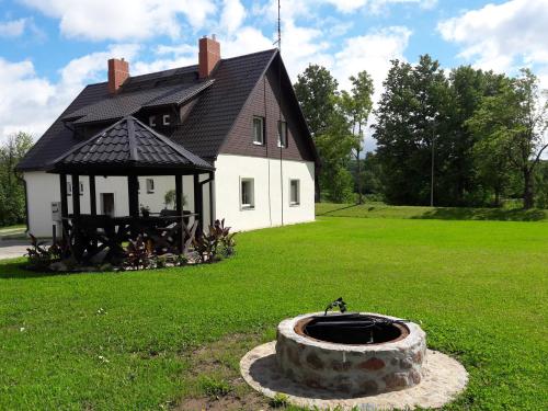 una casa con un grifo en un patio con un neumático grande delante en Ergli Holiday Apartments, en Ērgļi