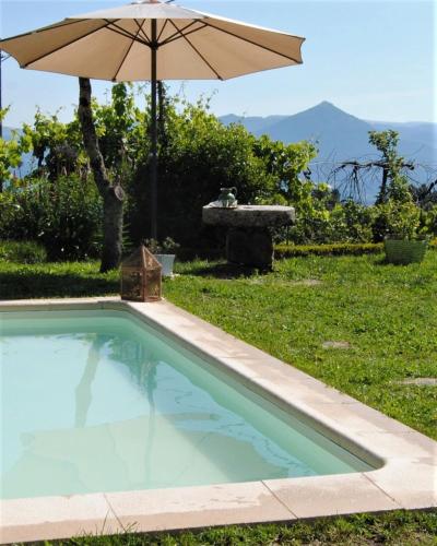 a swimming pool with an umbrella and a table at Casa de Cerqueda in Celorico de Basto