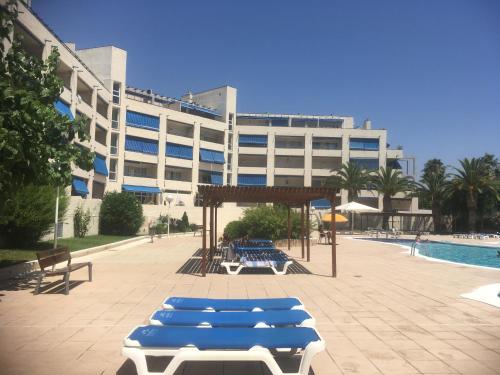 a building with blue lounge chairs in front of a pool at Punta Prima 229 in La Pineda