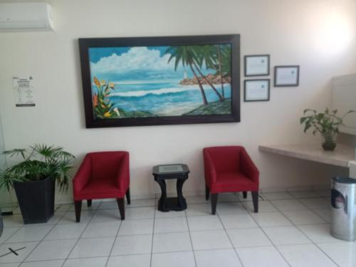 ein Wartezimmer mit zwei roten Stühlen und einem Gemälde an der Wand in der Unterkunft Hotel California in Tuxpan de Rodríguez Cano
