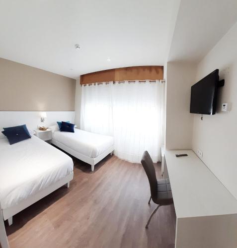 a hotel room with two beds and a television at Hotel La Terraza in Miño
