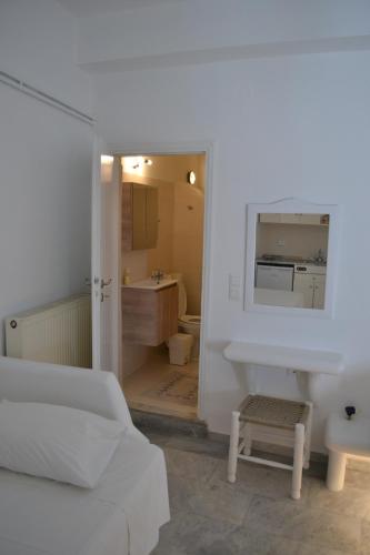 Jest to biały pokój z białym łóżkiem i łazienką. w obiekcie Studio Ioanna Tinos w mieście Kionia