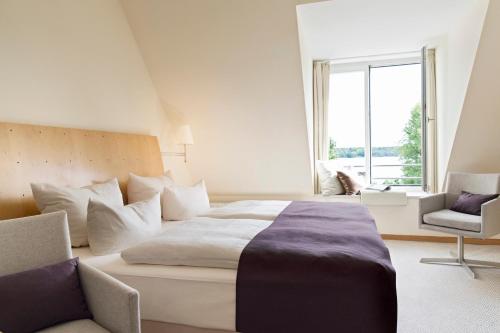 
a room with a bed, a chair, and a window at Hotel Kleines Meer in Waren
