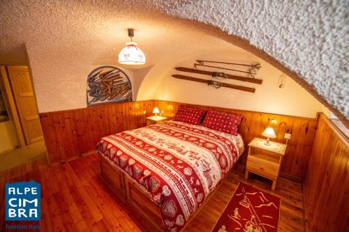 1 dormitorio con 1 cama con colcha roja en La stube degli sciatori, en Serrada