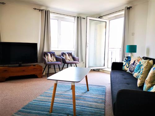 a living room with a couch and a tv at Marina living with parking, balcony, quiet and secure in Brighton & Hove