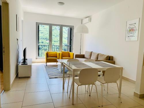 a white living room with a table and chairs at Lavender Bay Apartment E7 in Donji Morinj