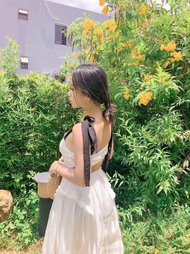 a girl in a white dress standing in front of a bush at Coto Center Homestay in Dao Co To