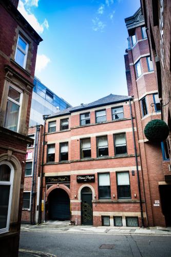 a red brick building with an archway on a street at Luxury Travel Emporium LS1 - Luxury City Centre Apartments in Leeds