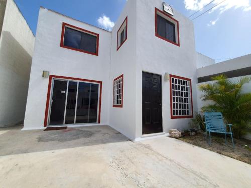 a white house with a blue chair in front of it at HOSPEDAJE HOLY in Mérida