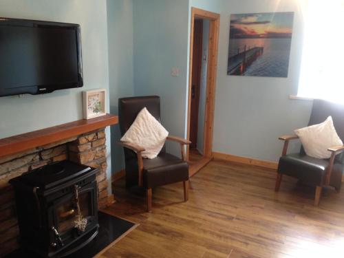 a living room with a fireplace and a flat screen tv at Glaslough Ramblers Rest in Monaghan