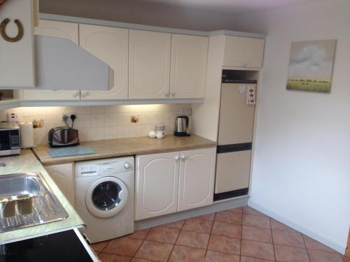 a kitchen with white cabinets and a washing machine at Glaslough Ramblers Rest in Monaghan