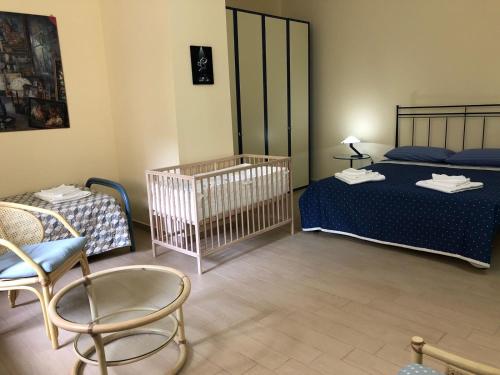 タオルミーナにあるCapo Taormina Houseのベッド2台、椅子、ベビーベッド1台が備わる客室です。