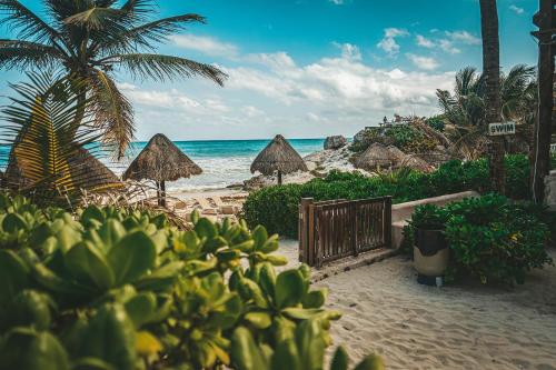 a beach with a gate and umbrellas and the ocean at La Conchita Tulum in Tulum