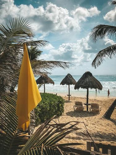 a beach with umbrellas and chairs and the ocean at La Conchita Tulum in Tulum