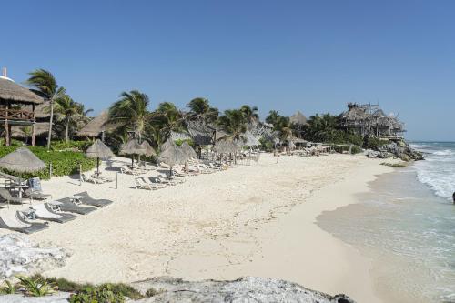 a beach with chairs and umbrellas and the ocean at La Conchita Tulum in Tulum