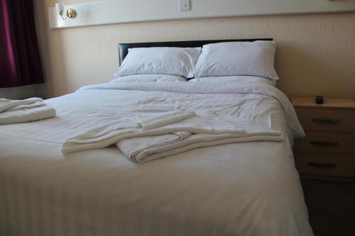 a bed with white blankets and pillows on it at Croxdale Inn in Durham