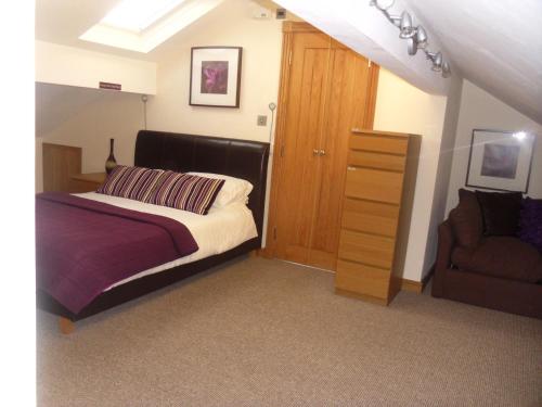 1 dormitorio con 1 cama, vestidor y silla en The Arc - Boutique B&B, en Harrogate