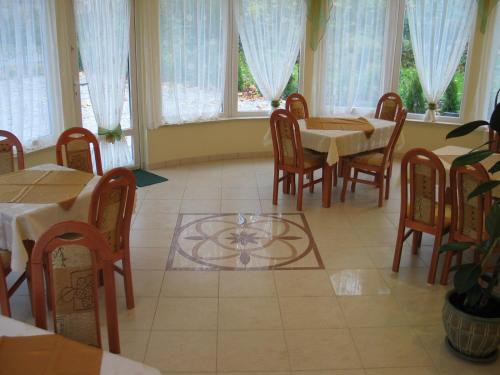 jadalnia ze stołami, krzesłami i oknami w obiekcie Hotel Pod Platanami w mieście Trzebnica