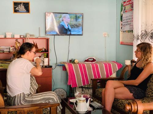two women sitting in a living room watching a tv at VILLA 826 Ahungalla in Ahungalla