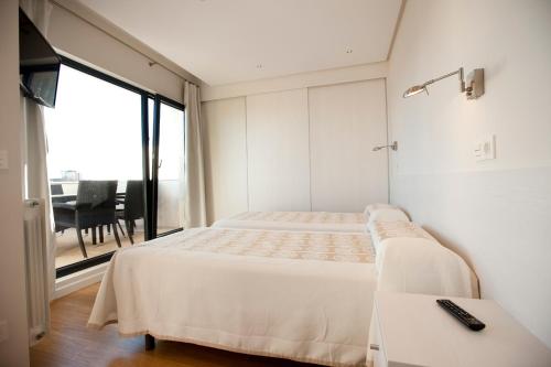 a bedroom with two beds and a table and a window at Costa Quebrada Apartamentos in Soto de la Marina