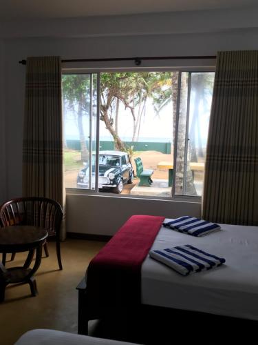 a bedroom with a bed and a window with a car outside at Villa Whispering Shells in Kalutara