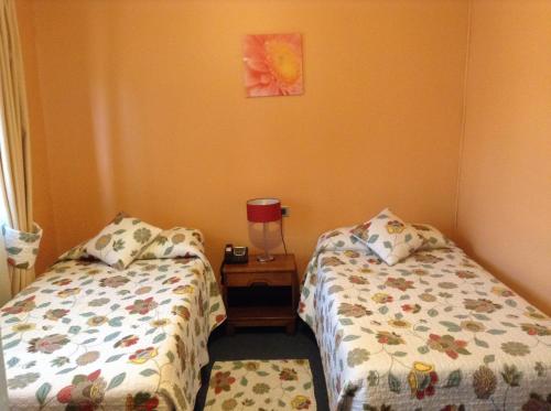 a bedroom with two beds and a table with a lamp at Hotel Le Mirage in Puerto Montt