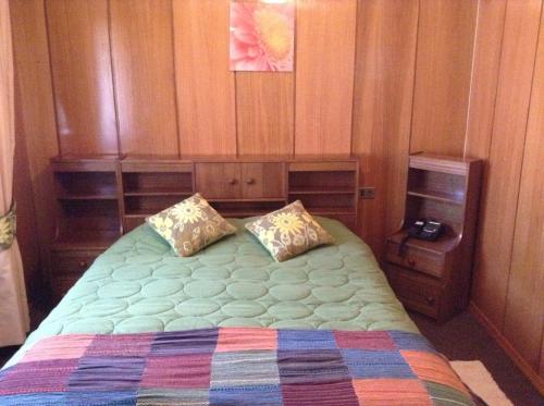 1 dormitorio con 1 cama grande y paredes de madera en Hotel Le Mirage, en Puerto Montt