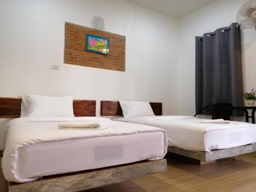 a bedroom with two beds and a brick wall at เพ็ญวิวรีสอร์ท in Ban Dong Sai