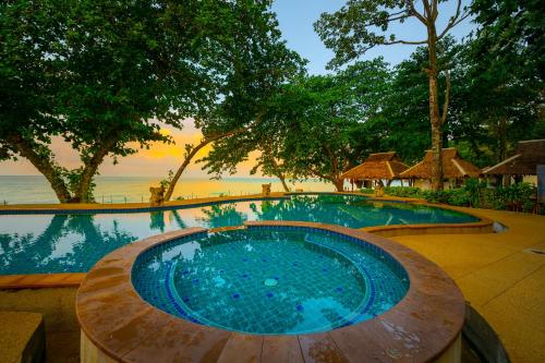 een groot zwembad met een houten tafel naast de oceaan bij Siam Beach Resort in Ko Chang