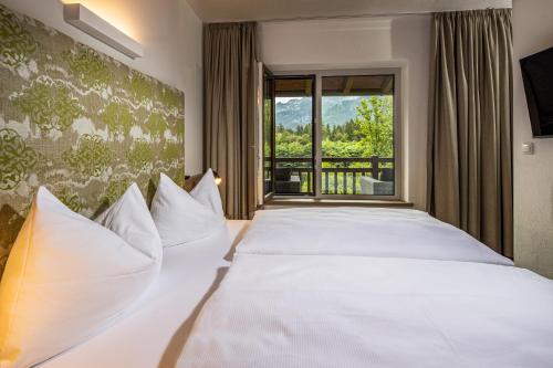 Schlafzimmer mit einem großen weißen Bett und einem Fenster in der Unterkunft Ferienwohnungen am Gablerhof in Bad Reichenhall