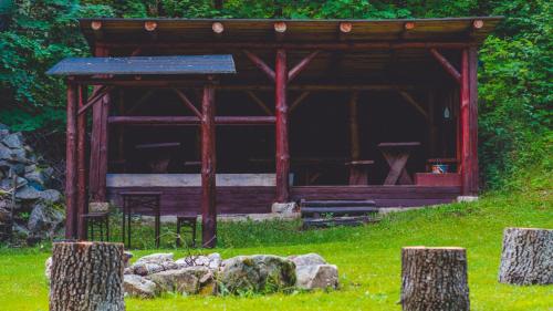 a wooden pavilion in a field with some rocks at Leśniczówka pod Śnieżką in Bukowiec