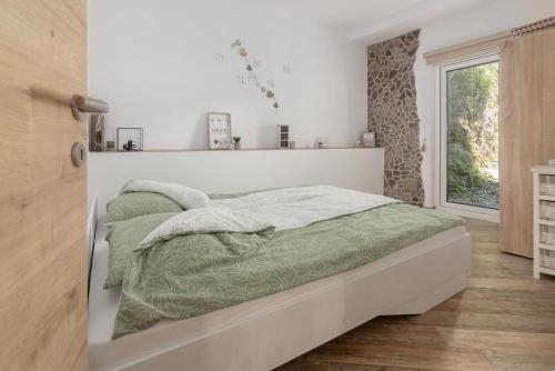 a white bedroom with a bed with green comforter and pillows at Apartment Bohinj in Bohinj