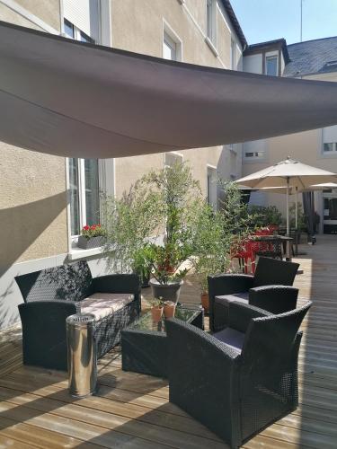 a patio with couches and tables and an umbrella at Logis Hotel - Le Charleston in Le Mans