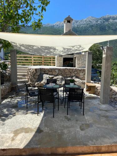 a patio with a table and chairs and a stone fireplace at Mate in Zagvozd