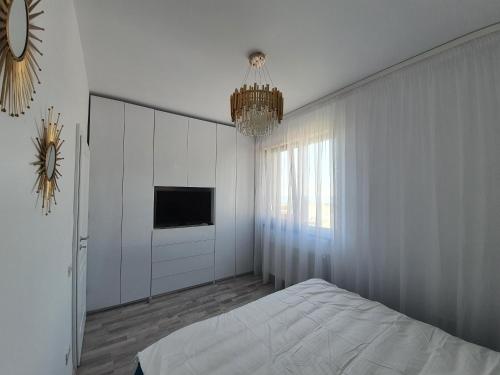 a bedroom with a bed and a tv and a chandelier at Apartament Lux Eika in Mamaia Sat/Năvodari