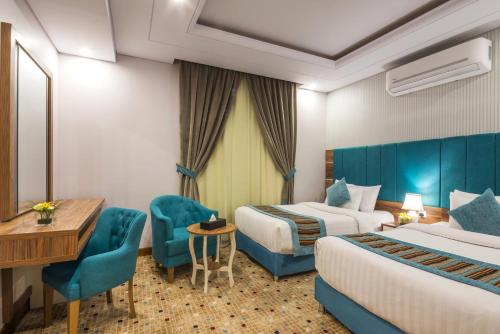 a hotel room with two beds and a desk and chairs at Le Park Concord Hotel - Turaif in Ţurayf