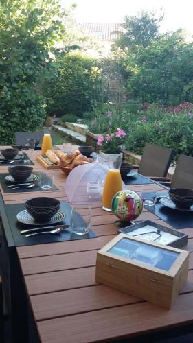 una mesa de madera con platos y vasos. en Domaine de la Fée-Licité, en Jullié