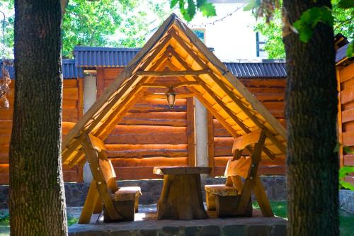 a wooden cabin with a table and two trees at Hotel Praha in Uzhhorod