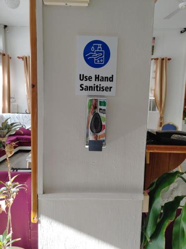 a sign on a wall that reads use hand sanitizer at Orient Guesthouse Auberge in Mahébourg