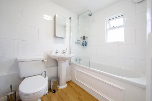 a white bathroom with a toilet and a sink at The Old Bakery in Falmouth