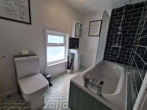 a bathroom with a toilet and a sink and a tub at Ty Morgan's Apartments in Rhayader
