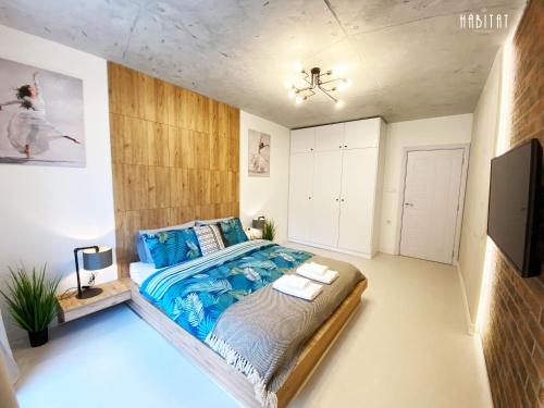 a bedroom with a large bed with a blue comforter at habitat The River Apartment in Ruse