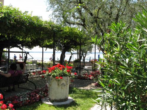 two people sitting on a bench in a park with flowers at Hotel Giardino in Sirmione