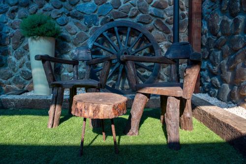 two wooden chairs and a stool next to a wheel at At Gil's and Galit's Place- Hospitality, Health and Spa in Bruchim Qela' Alon