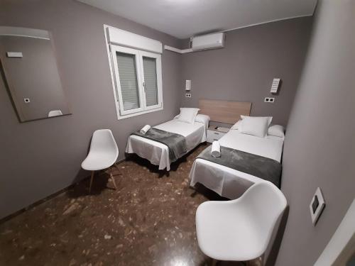 a bedroom with two beds and two chairs and a mirror at AYAMONTE ROOMS 43 in Ayamonte